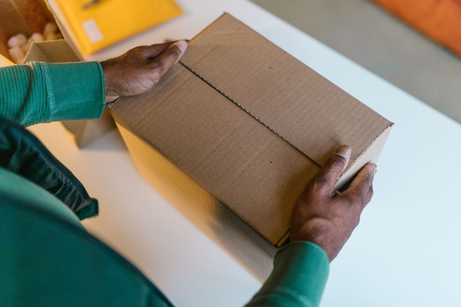Hands taping a cardboard shipping box closed