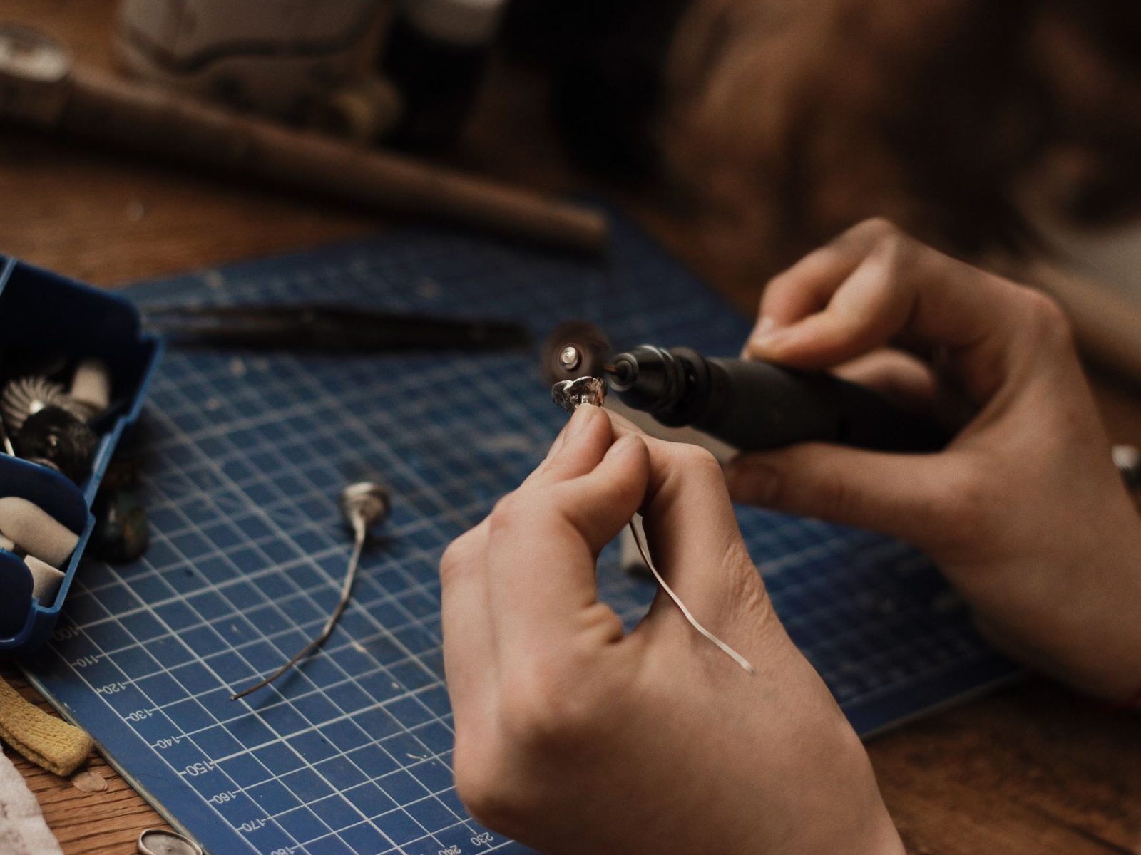 Hands working with a small tool on a cutting mat