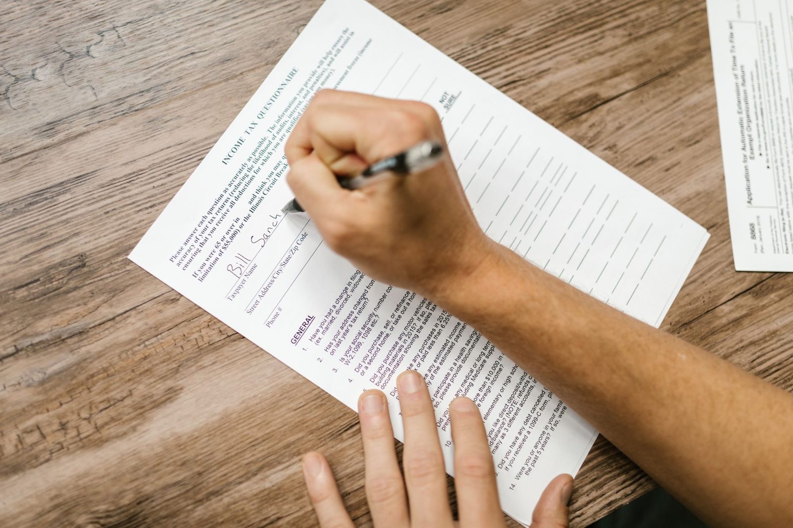 Person filling out a paper form at a desk