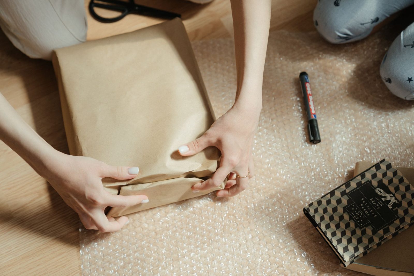 Hands wrapping a package in bubble wrap and paper for shipping