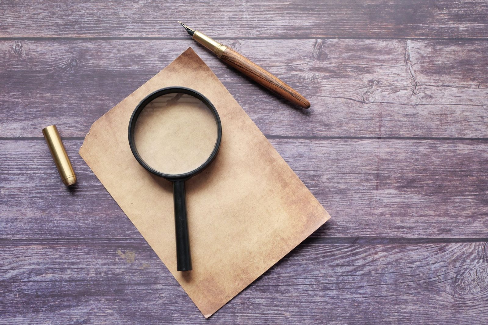 Magnifying glass resting on paper on a wooden desk